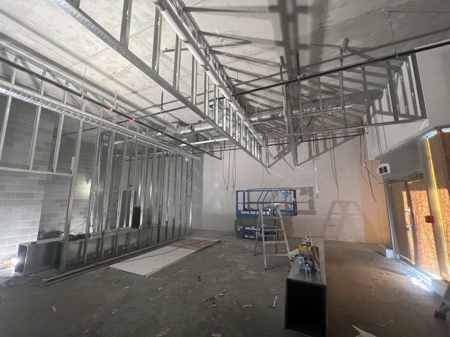 Steel stud ceiling grid and bulkhead framing over an open concrete floor with a scissor lift
